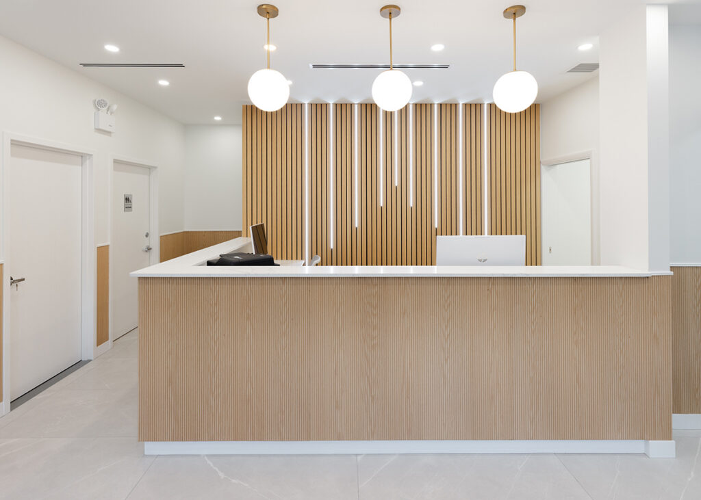 Reception desk with a wood-slat wall and pendant lights